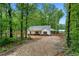 Exterior view of single story home on a tree covered lot with gravel driveway at 1765 Harmony Rd, Temple, GA 30179