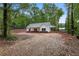 Charming, newly built single-story home with light gray roof, light siding and gravel driveway surrounded by trees at 1765 Harmony Rd, Temple, GA 30179