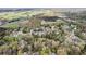 A birds eye view of a neighborhood filled with mature trees, complemented by distant farmlands at 65 Indian Springs Ne Dr, Rydal, GA 30171