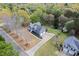 An aerial view of a gray home with a two-car garage, a long driveway, and a backdrop of lush, mature trees at 65 Indian Springs Ne Dr, Rydal, GA 30171