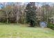 View of the lush backyard with a shed perfect for storage or a hobby space surrounded by mature trees at 65 Indian Springs Ne Dr, Rydal, GA 30171