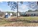 View of the backyard featuring a shed and the back of the home with a wooden deck. Landscaped with grass and some trees at 2003 Graystone Pkwy, Grayson, GA 30017