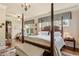 Spacious primary bedroom featuring a four-poster bed, hardwood floors, sitting area and large windows at 115 Batten Board Way Way, Woodstock, GA 30189