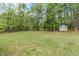 Spacious backyard with green grass, a shed, and surrounding trees at 85 Emily Trce, Covington, GA 30016