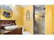 Bright yellow bathroom with a vessel sink, wood vanity, and glass shower with a pebble floor at 104 Kremer Falls Trce, Canton, GA 30114
