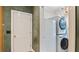 Convenient laundry room with stacked washer and dryer units next to a utility sink and door at 104 Kremer Falls Trce, Canton, GA 30114
