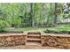 Landscaped backyard with stone steps, lush greenery, and a fenced perimeter at 9770 Rod Rd, Alpharetta, GA 30022