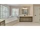 Bright bathroom with a large soaking tub under decorative leaded glass window at 9770 Rod Rd, Alpharetta, GA 30022