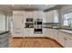 Spacious kitchen boasts stainless appliances, white cabinets, and hardwood floors, seamlessly blending style and functionality at 9770 Rod Rd, Alpharetta, GA 30022