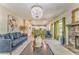 Spacious living room with plush blue sofa, stone fireplace, and modern chandelier at 1302 Gardenia Ct, Villa Rica, GA 30180