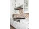 Gourmet kitchen showcasing stainless steel appliances, custom cabinetry, a brick backsplash, and white countertops at 4356 Jenkins Ne Dr, Roswell, GA 30075