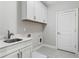 Well-appointed laundry room with sink, cabinets, and gray tile flooring at 4356 Jenkins Ne Dr, Roswell, GA 30075