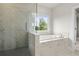 Bathroom featuring marble style tiling, a glass-enclosed shower, and a separate soaking tub under a window at 631 Skytop Dr, Cumming, GA 30040