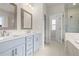 Bright bathroom featuring double vanity with blue cabinets, marble flooring, soaking tub and glass-enclosed shower at 631 Skytop Dr, Cumming, GA 30040