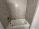 Modern bathtub with beautiful gray tile surround, complemented by sleek bronze fixtures at 631 Skytop Dr, Cumming, GA 30040