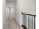 Hallway with neutral carpet, white walls, a wooden handrail, and multiple doors, bathed in natural light at 631 Skytop Dr, Cumming, GA 30040