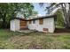 Exterior view of the backyard, showing the layout and brick siding of the home and an overgrown lawn at 1809 San Gabriel Ave, Decatur, GA 30032