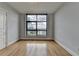 An empty bedroom with light walls, wooden floors, and a large window showcasing an urban view at 750 Park Ne Ave # 13E, Atlanta, GA 30326