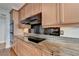 Close-up of the kitchen with updated appliances, wood cabinets, and granite countertops at 750 Park Ne Ave # 13E, Atlanta, GA 30326