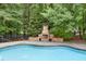 Backyard stone fireplace with built-in seating next to the pool and lush trees at 2788 Bridle Ridge Way, Buford, GA 30519