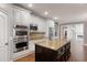 Open kitchen featuring a dark island, white cabinets, stainless appliances, and hardwood floors at 2788 Bridle Ridge Way, Buford, GA 30519