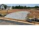 Graded homesite with gravel driveway, silt fencing, and a view of new home construction in the background at 668 Crest Line Trl, Powder Springs, GA 30127