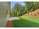 Beautiful backyard with green grass and a concrete patio on a sunny day, next to green home at 699 Crest Line W Trl, Powder Springs, GA 30127