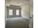 Spacious bedroom featuring plush gray carpeting, two windows, and a tray ceiling at 3908 Shelleydale Dr, Powder Springs, GA 30127