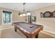 The carpeted game room is lit by a chandelier above a pool table with equipment at 1455 Oglethorpe Run Ln, Suwanee, GA 30024
