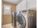 Functional laundry room with front-load washer and dryer, white cabinets, and a window at 1455 Oglethorpe Run Ln, Suwanee, GA 30024