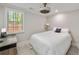 Bright bedroom features white bedding, contemporary fan, and large window providing natural light at 2376 Academy Ne Ct, Atlanta, GA 30345