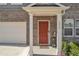 Inviting front entrance with a red door, decorative columns, and manicured landscaping at 5372 Fountain Head Ln, Auburn, GA 30011
