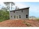 View of the house's rear gray siding, featuring large windows and a door that leads to the unfinished yard space at 1097 Bodega Loop, Locust Grove, GA 30248