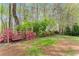 Serene backyard with a charming swing bench surrounded by vibrant pink azaleas and lush trees at 1870 Chattahoochee Run Dr, Suwanee, GA 30024