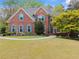 Inviting two-story brick home with a lush green lawn, complemented by mature landscaping and a welcoming entrance at 1870 Chattahoochee Run Dr, Suwanee, GA 30024