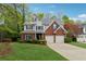Charming two-story home featuring a brick facade, gray siding, a well-manicured lawn, and an attached two-car garage at 310 Kingspring Ct, Roswell, GA 30076