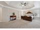 A large, carpeted main bedroom with a tray ceiling, a ceiling fan, and windows that let in natural light at 310 Kingspring Ct, Roswell, GA 30076