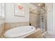 Bathroom featuring a soaking tub, glass shower, and neutral tile, offering a relaxing and spa-like atmosphere at 95 Nesbit Reserve Ct, Alpharetta, GA 30022