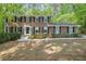 Charming two-story brick home with black shutters and a well-manicured front lawn in a wooded lot at 5145 Davantry Dr, Dunwoody, GA 30338
