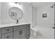 Modern bathroom with gray vanity, gold-trimmed round mirror, and tiled shower at 9429 Golfview Pt, Villa Rica, GA 30180