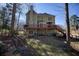 Rear exterior showcasing the wooden deck, patio, and backyard landscape surrounded by mature trees at 9600 Poplar Ct, Douglasville, GA 30135