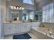 Elegant bathroom featuring soaking tub, large mirrors, double sinks, and bright natural light at 9600 Poplar Ct, Douglasville, GA 30135