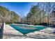 A fenced-in pool with a pool cover is surrounded by a patio on a treed property at 9600 Poplar Ct, Douglasville, GA 30135