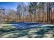 Daytime view of fenced tennis court with court lights, ready for year-round play at 9600 Poplar Ct, Douglasville, GA 30135