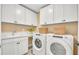 Bright laundry room featuring white cabinets, modern washer and dryer, and marble countertop at 307 Rockledge Sw Bnd, Powder Springs, GA 30127