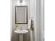 Elegant half bathroom with a pedestal sink, framed mirror, and neutral color palette at 938 Catamaran Ct, Alpharetta, GA 30005