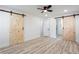 Bright main bedroom with wood flooring, ceiling fan, and stylish barn door to bathroom at 4506 Dorset Dr, Decatur, GA 30035