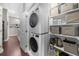 Bright laundry area featuring a stackable washer/dryer and organized shelving with storage containers at 6088 Holly Park Se Ln, Mableton, GA 30126