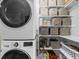 Bright laundry room with modern stackable washer and dryer, and shelving with storage boxes at 6088 Holly Park Se Ln, Mableton, GA 30126