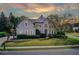 Elegant two-story home with manicured front lawn and mature landscaping under a colorful sky at 1900 Denton Walk Ct, Marietta, GA 30062